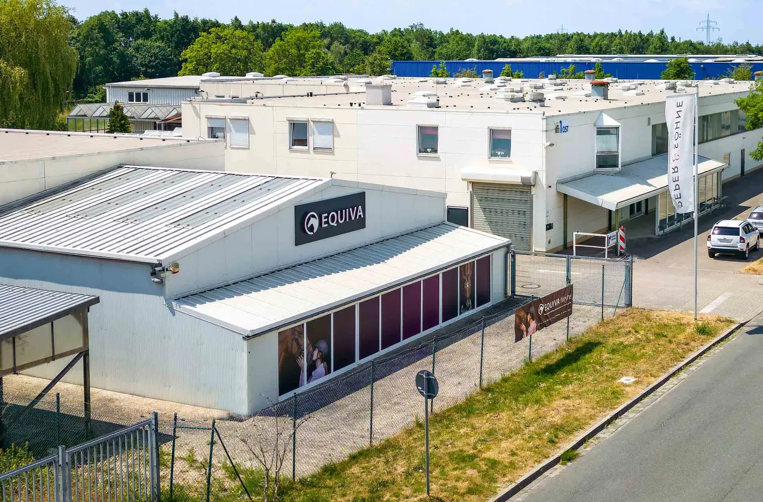 Foto der Lagerhalle. Dargestellt ist der Gewerbehof mit einer großen Lagerhalle und einem Haus mit der Aufschrift "EQUIVA".